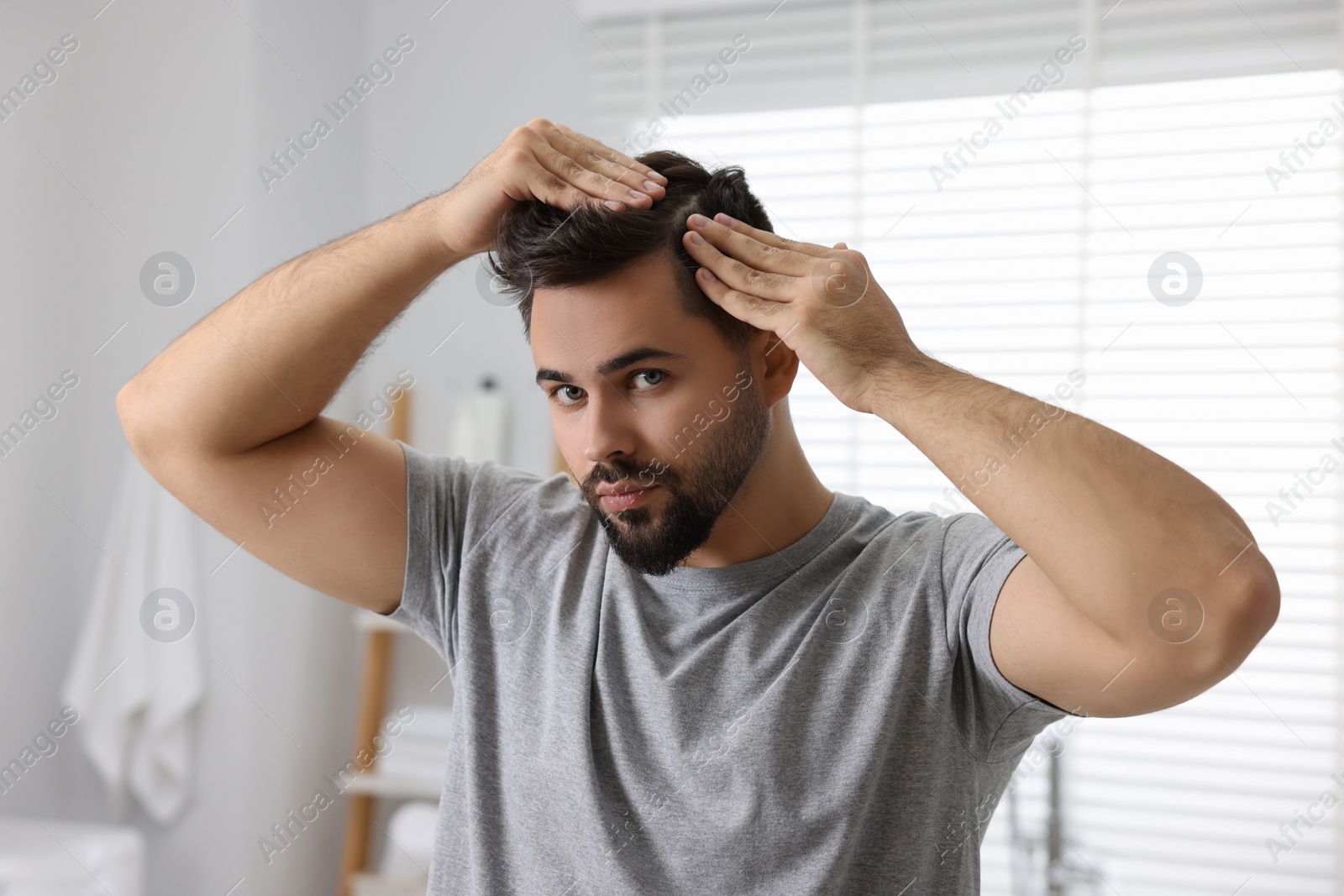 Photo of Man examining his head in bathroom. Dandruff problem