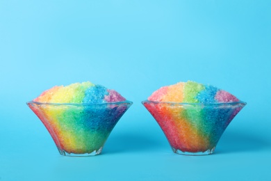 Photo of Rainbow shaving ice in glass dessert bowls on light blue background