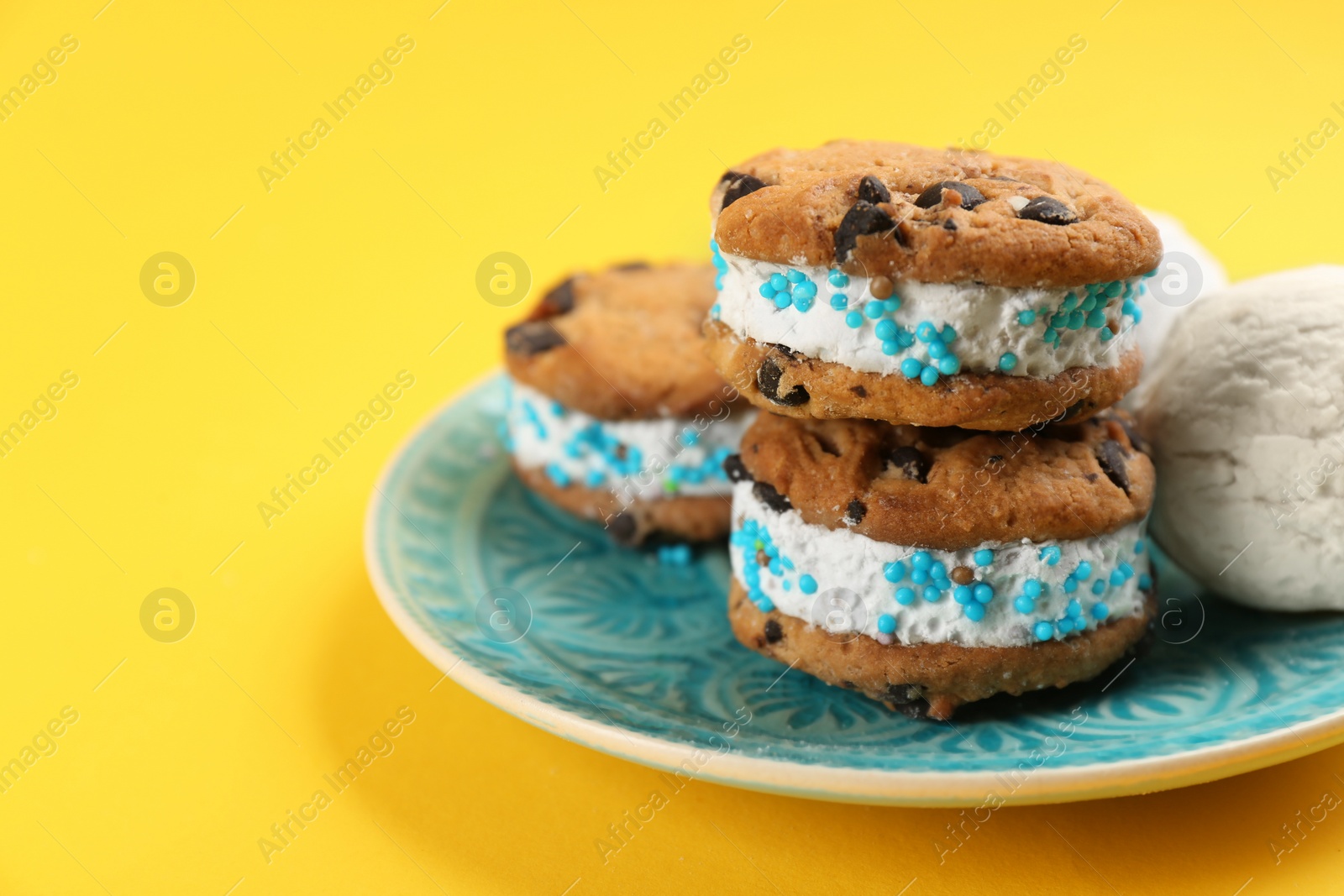 Photo of Sweet delicious ice cream cookie sandwiches on yellow background, closeup