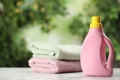 Stack of fresh towels and detergent on white marble table outdoors