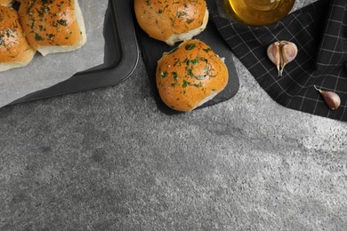 Traditional pampushka buns with garlic and herbs on grey table, flat lay. Space for text