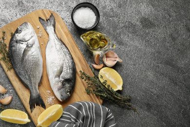 Flat lay composition with raw dorada fish on grey table, space for text
