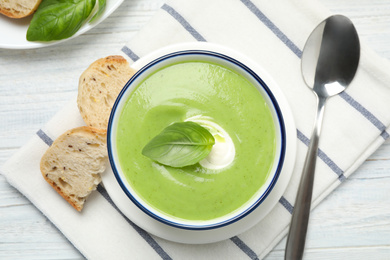 Photo of Tasty homemade zucchini cream soup served on white wooden table, flat lay