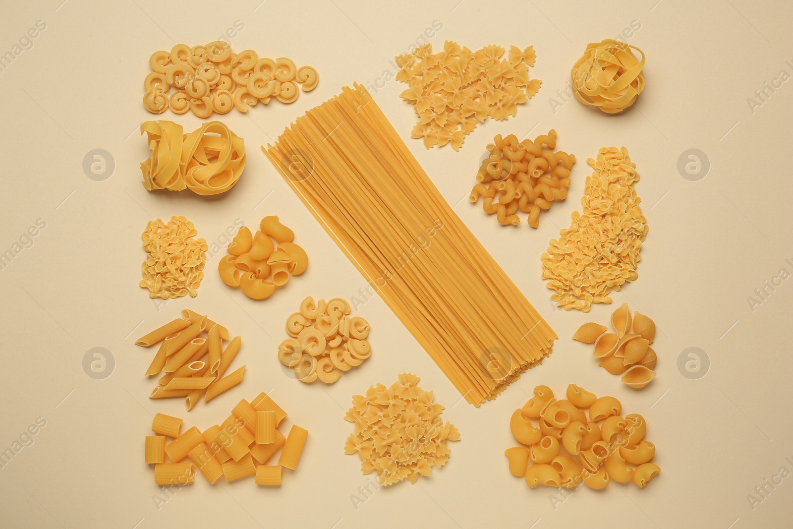 Photo of Different types of pasta on beige background, flat lay