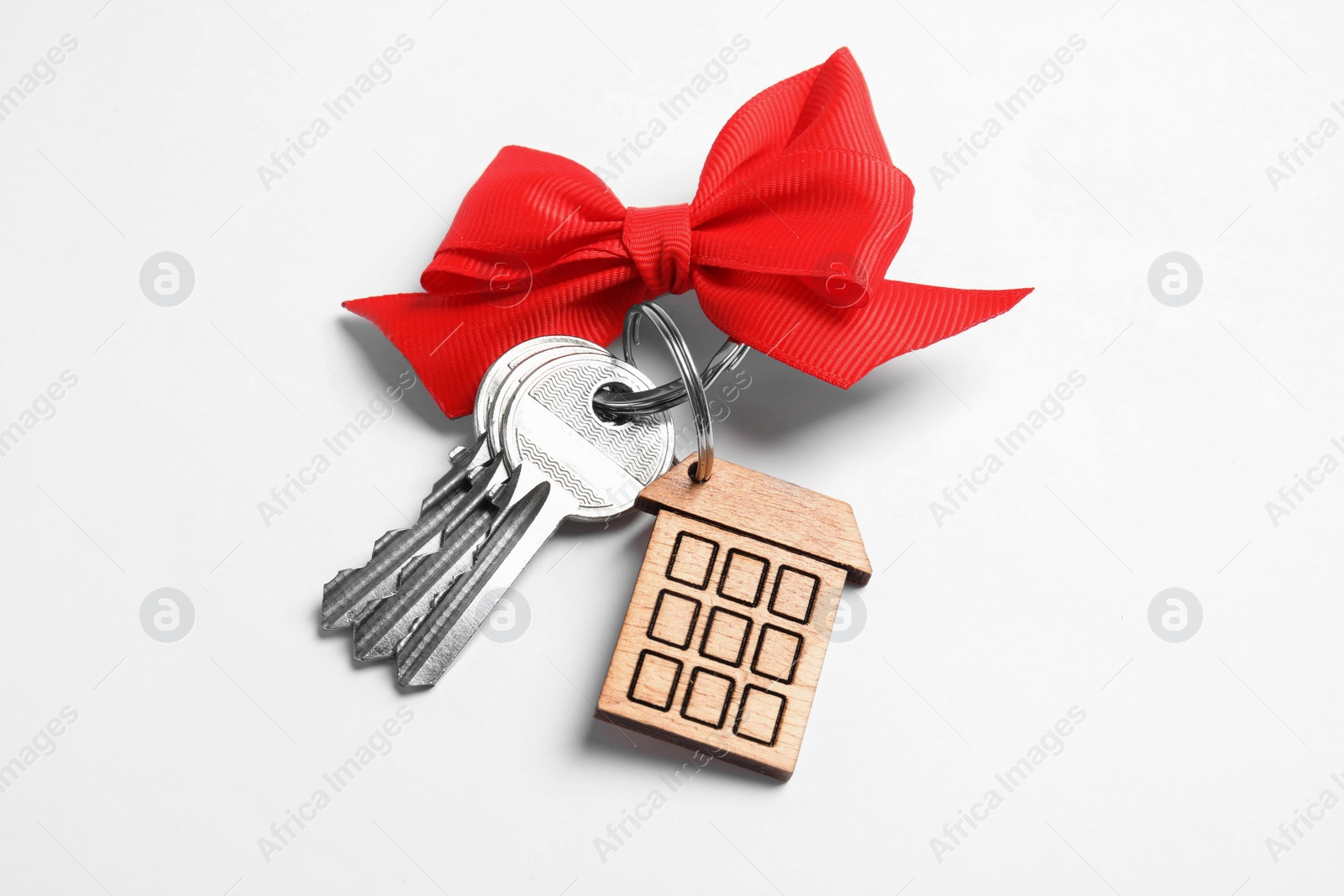 Photo of House keys with trinket and bow on white background