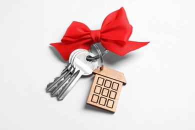 Photo of House keys with trinket and bow on white background