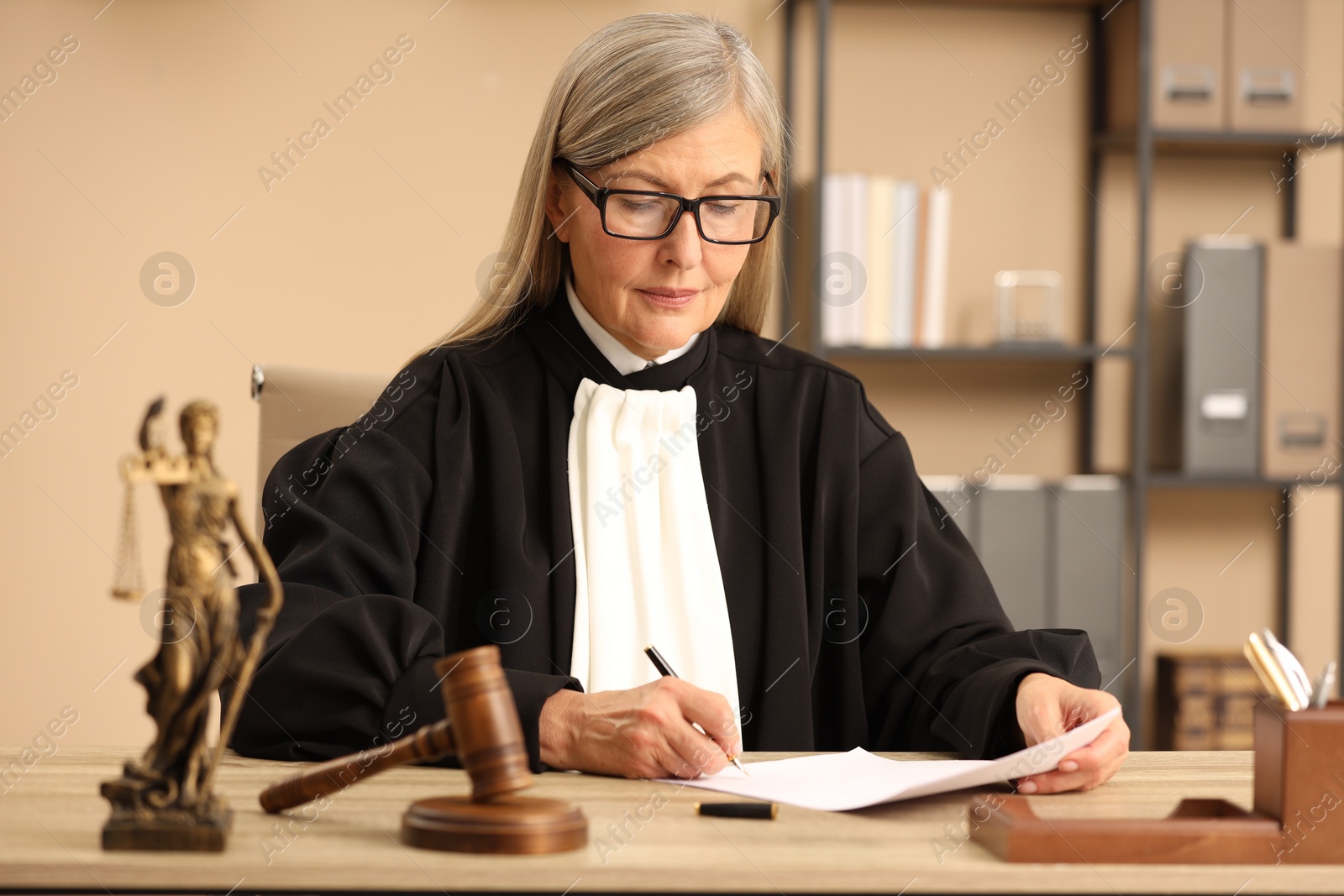 Photo of Judge in court dress working at table indoors