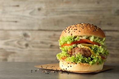 Photo of Burger with delicious patty on gray table, space for text