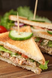 Delicious sandwiches with tuna and vegetables on wooden board, closeup