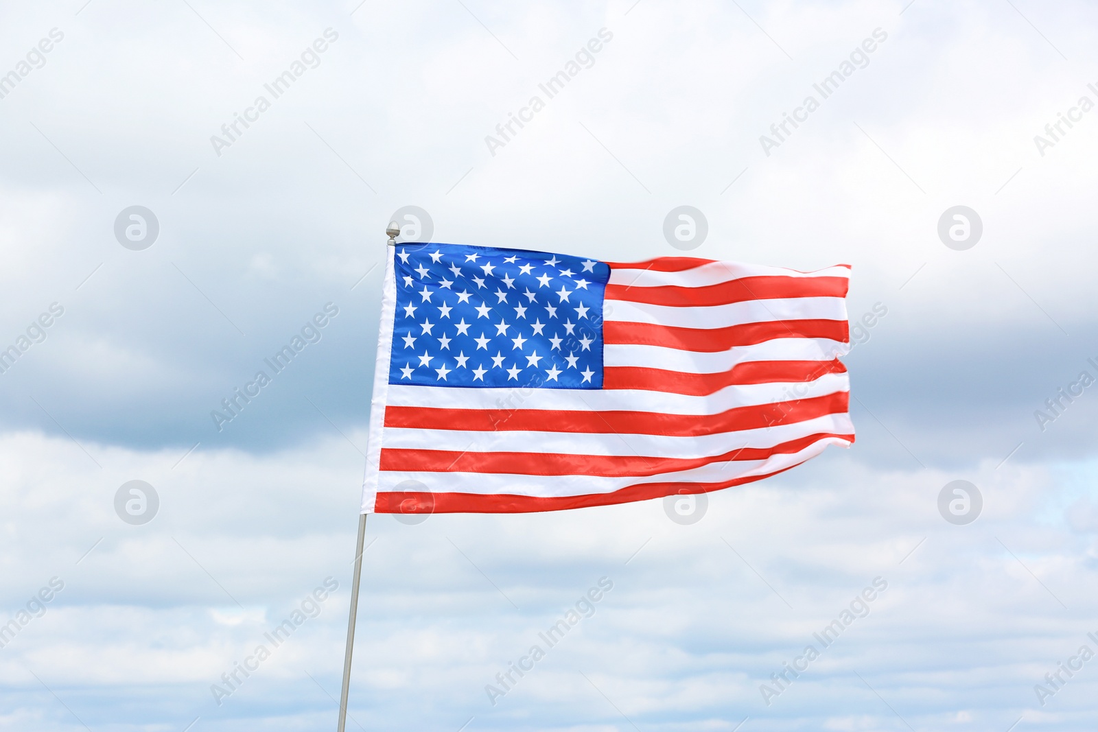 Photo of American flag fluttering outdoors on cloudy day