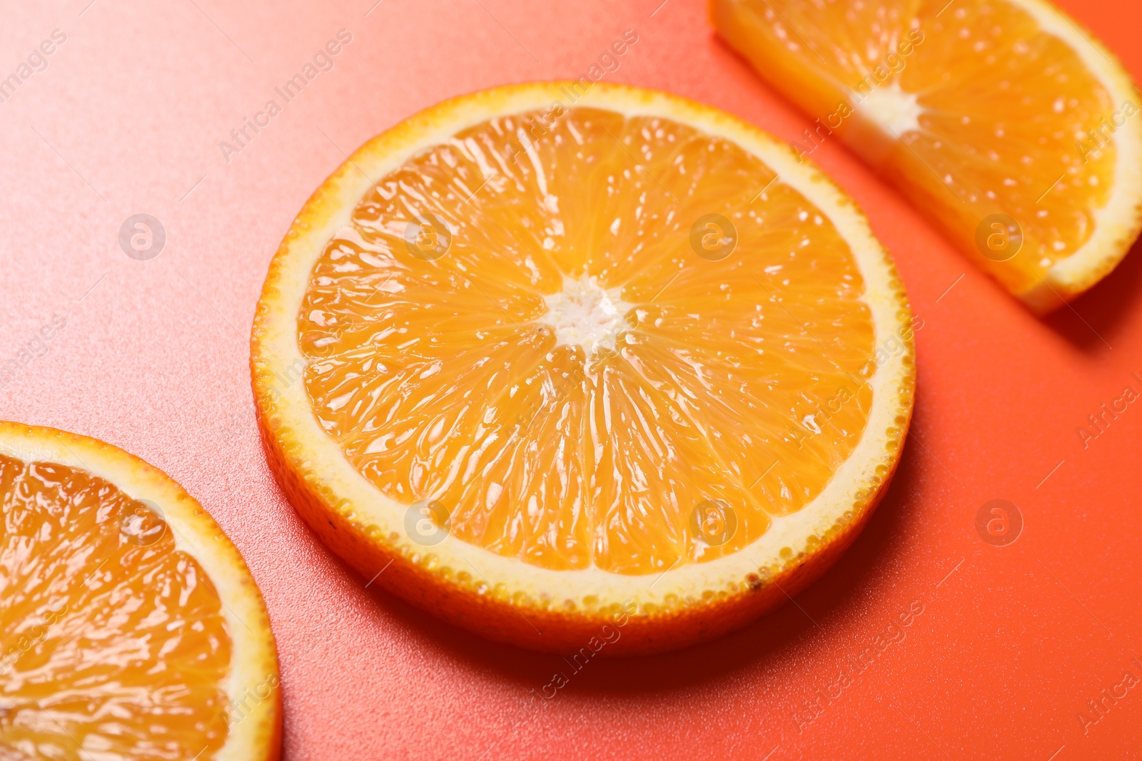 Photo of Slices of juicy orange on terracotta background, closeup