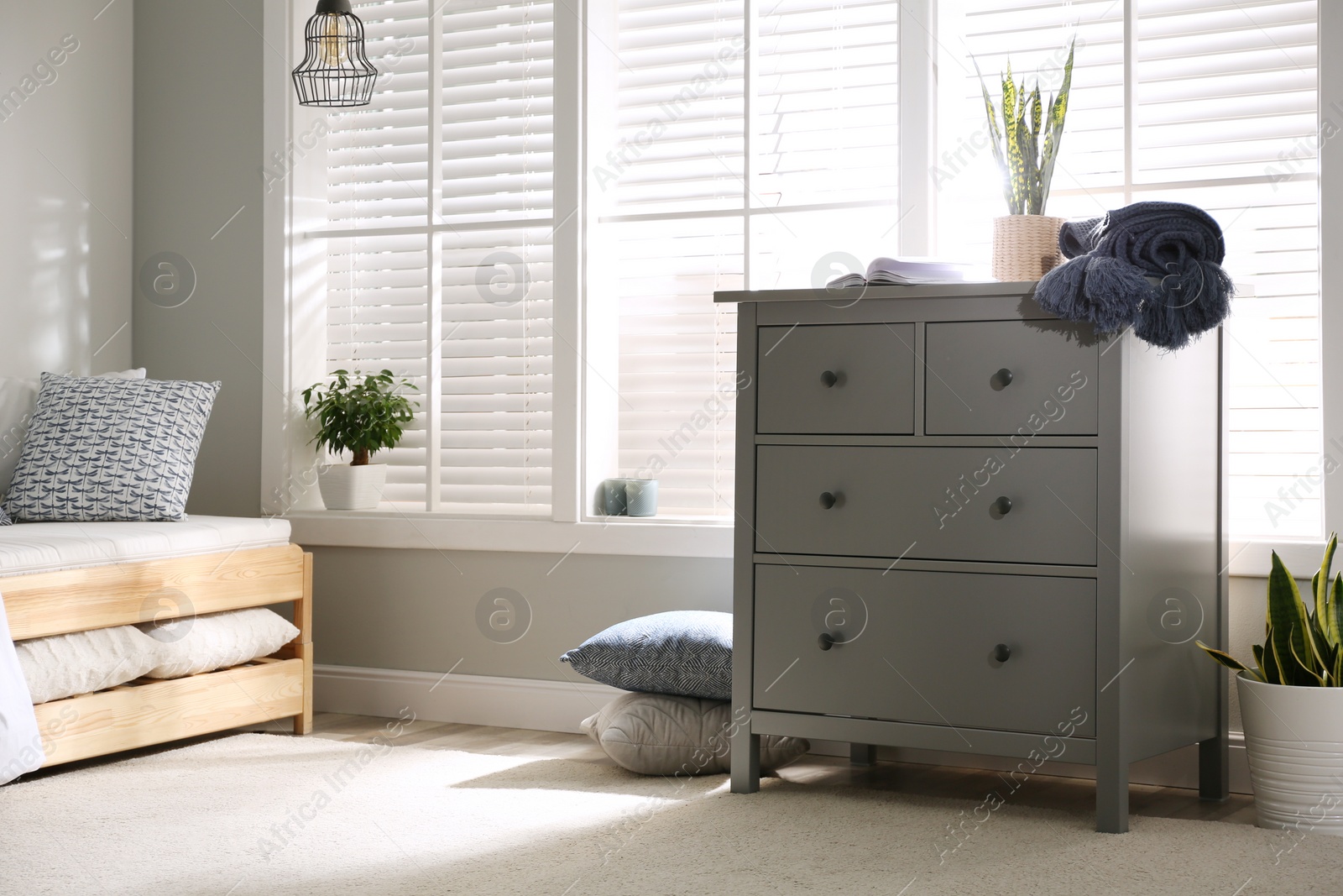 Photo of Grey chest of drawers near window in stylish bedroom interior