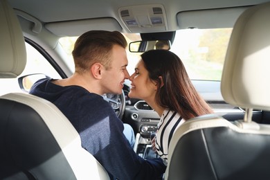 Photo of Happy young couple doing nose rub in car