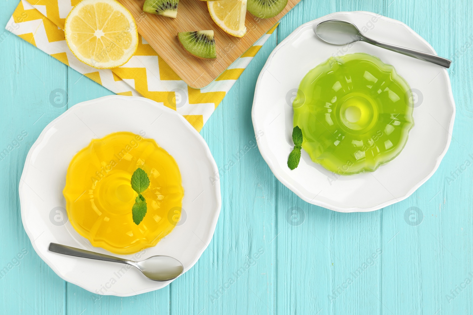 Photo of Flat lay composition with plates of jelly and tropical fruits on blue wooden table