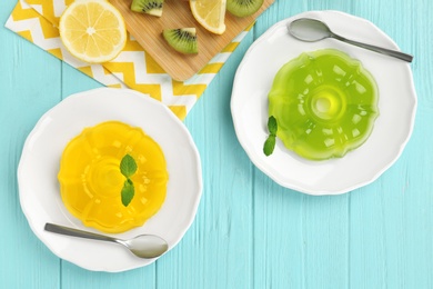 Flat lay composition with plates of jelly and tropical fruits on blue wooden table