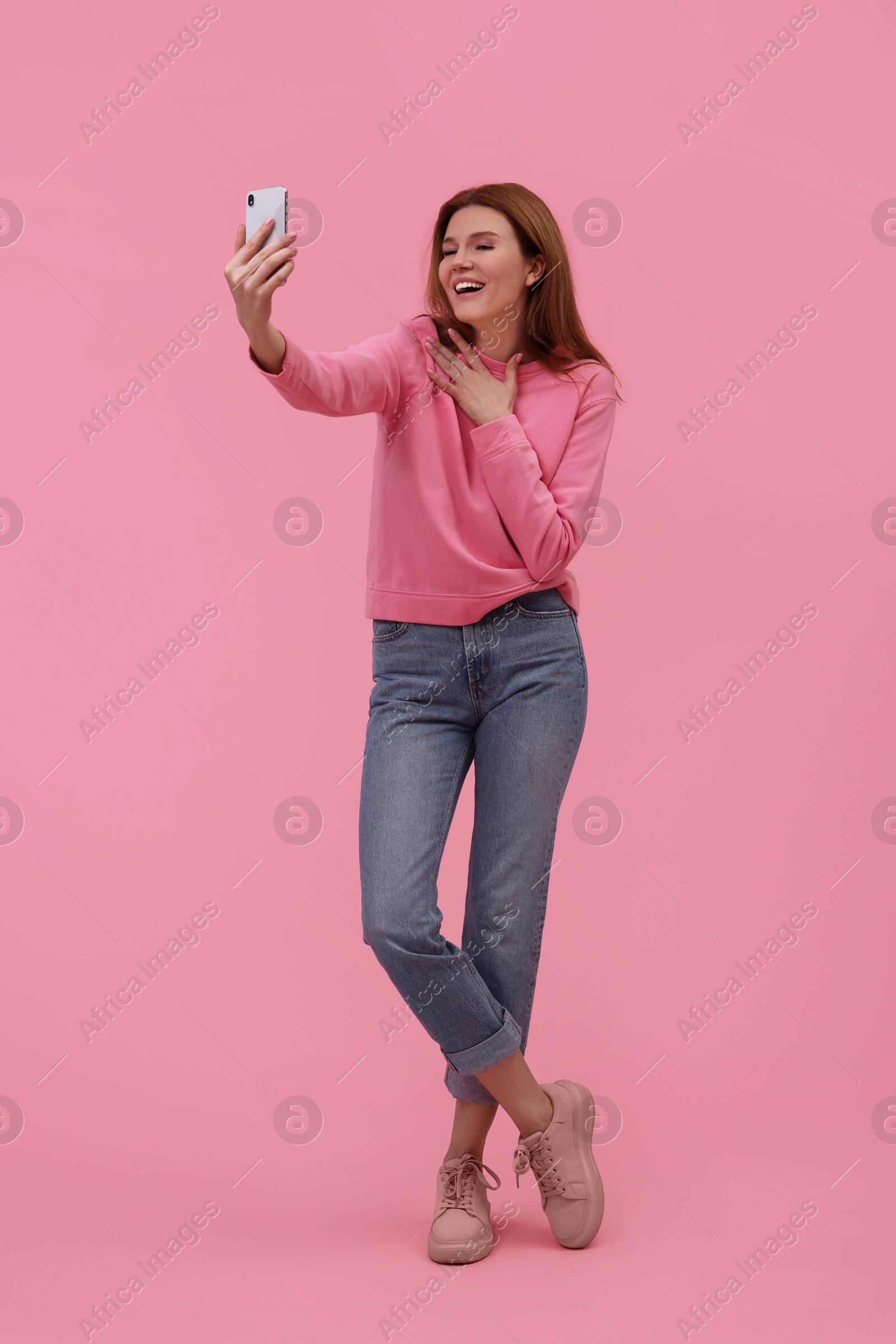 Photo of Beautiful woman taking selfie on pink background