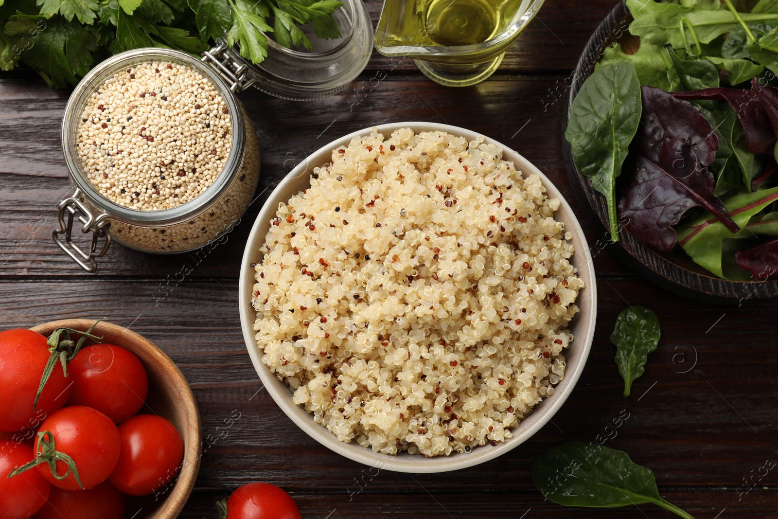 Photo of Tasty quinoa porridge in bowl, vegetables and seeds on wooden table, flat lay