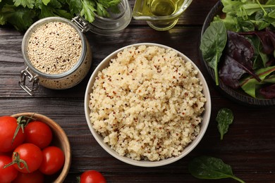 Photo of Tasty quinoa porridge in bowl, vegetables and seeds on wooden table, flat lay