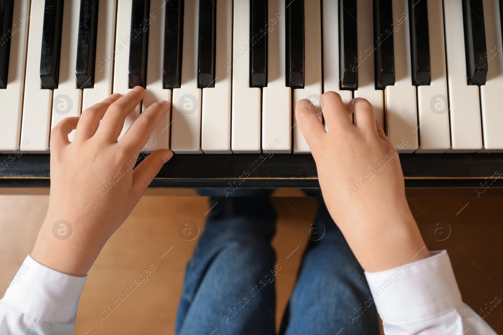 Photo of Little child playing piano, above view. Music lesson