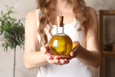 Young woman holding bottle of fresh olive oil, closeup