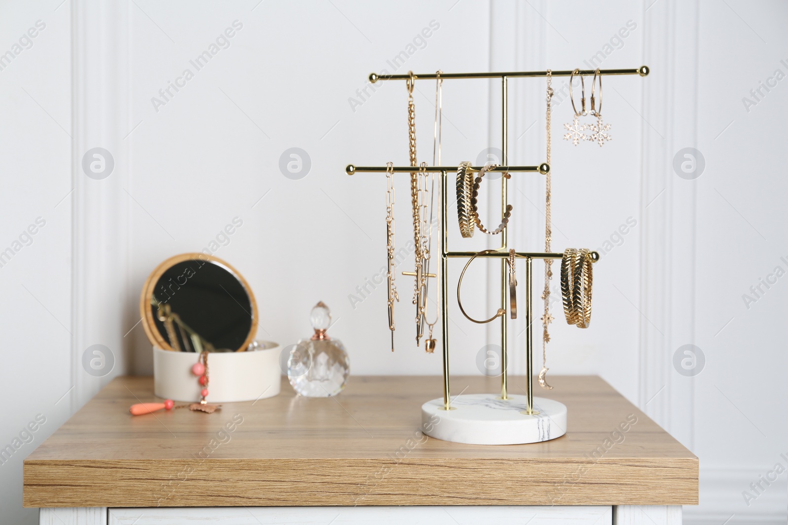 Photo of Interior element. Holder and casket with set of luxurious jewelry on wooden dressing table