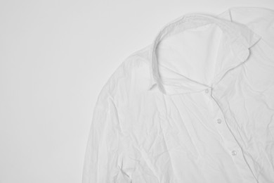 Photo of Crumpled shirt on white background, top view. Space for text