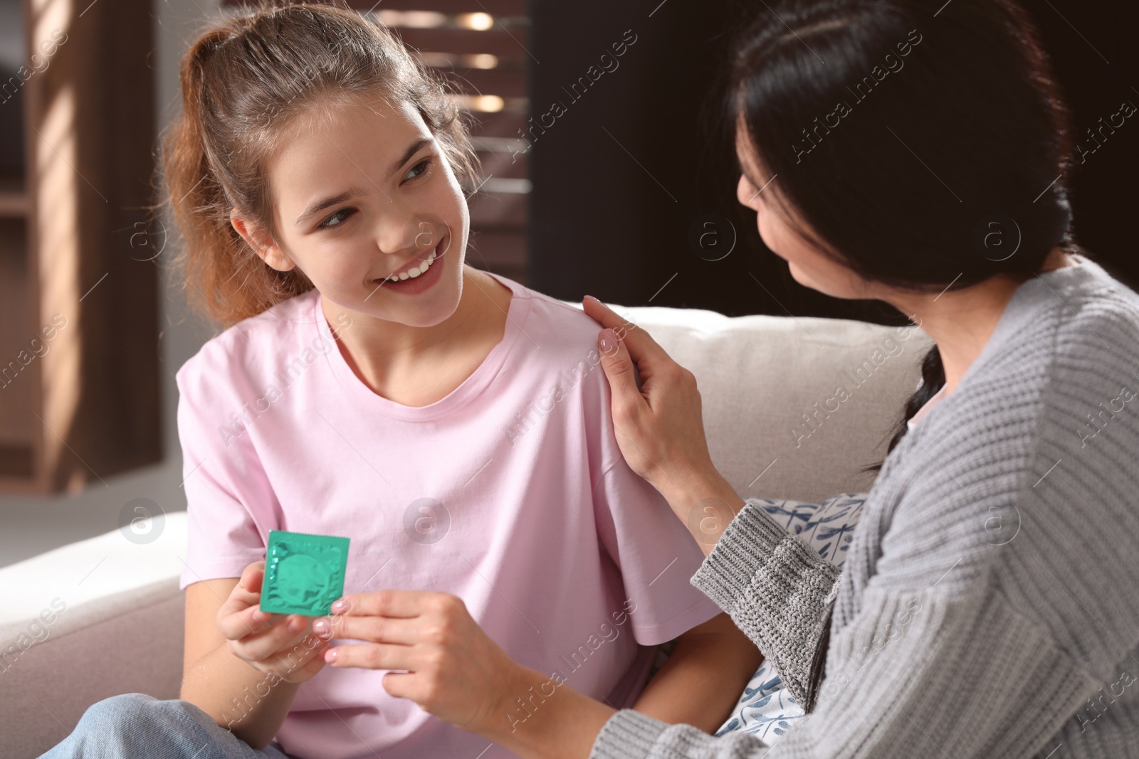 Photo of Mother giving condom to her teenage daughter at home. Sex education concept