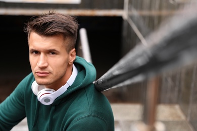 Portrait of handsome young man with headphones outdoors. Space for text