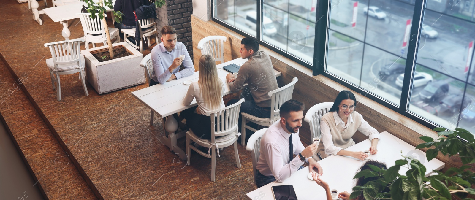 Image of Coworkers having coffee break near window in cafe, above view. Banner design