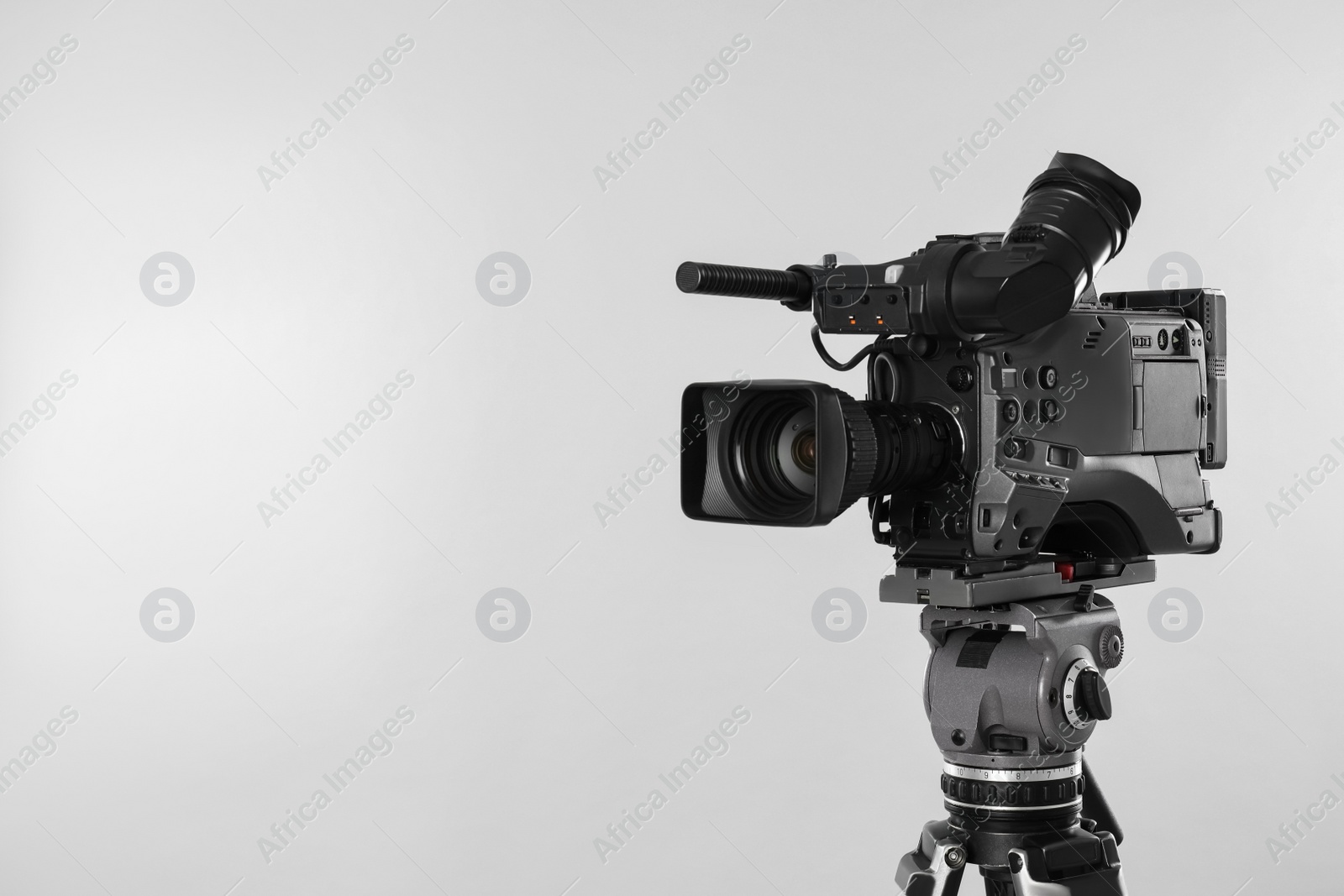 Photo of Modern professional video camera on light background. Space for text