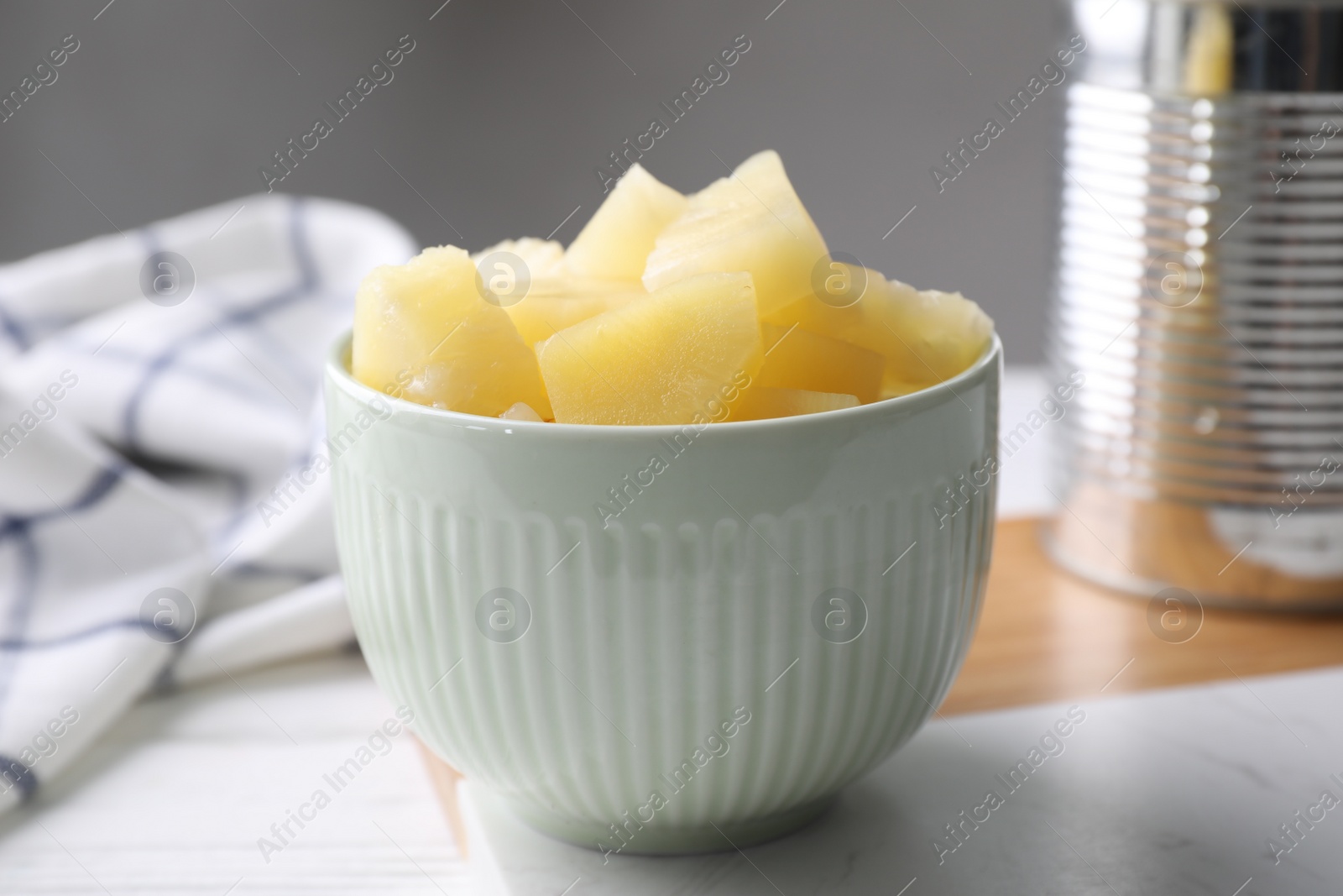 Photo of Pieces of canned pineapple in bowl on table, closeup