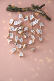 Christmas advent calendar with small gifts hanging on pink wall