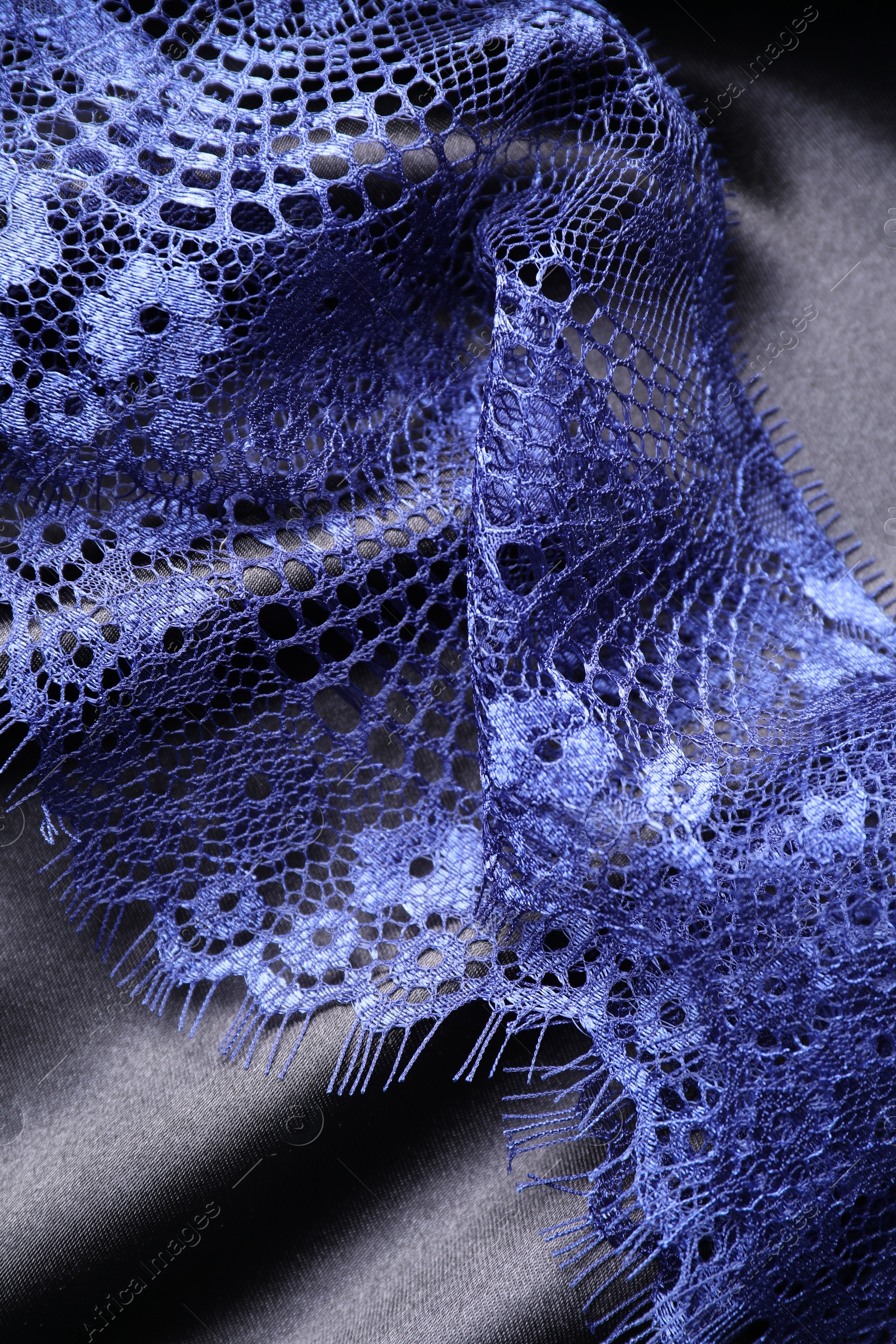 Photo of Beautiful blue lace on black fabric, top view