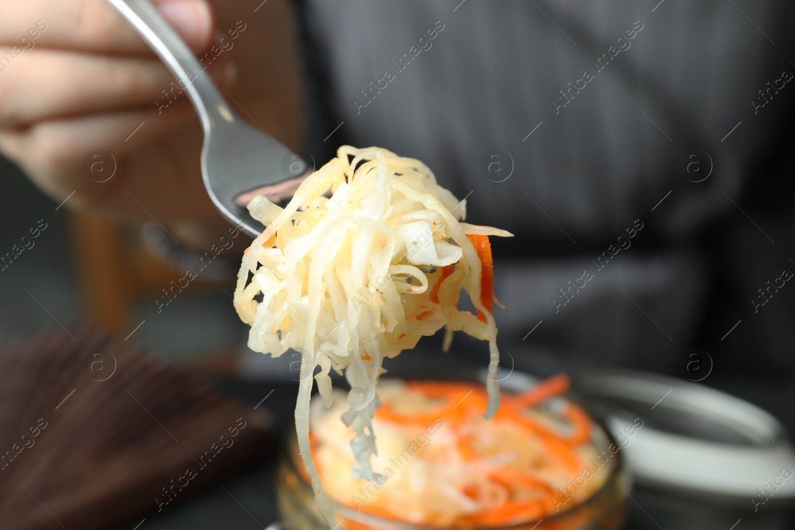 Photo of Woman holding fork with fermented cabbage, closeup