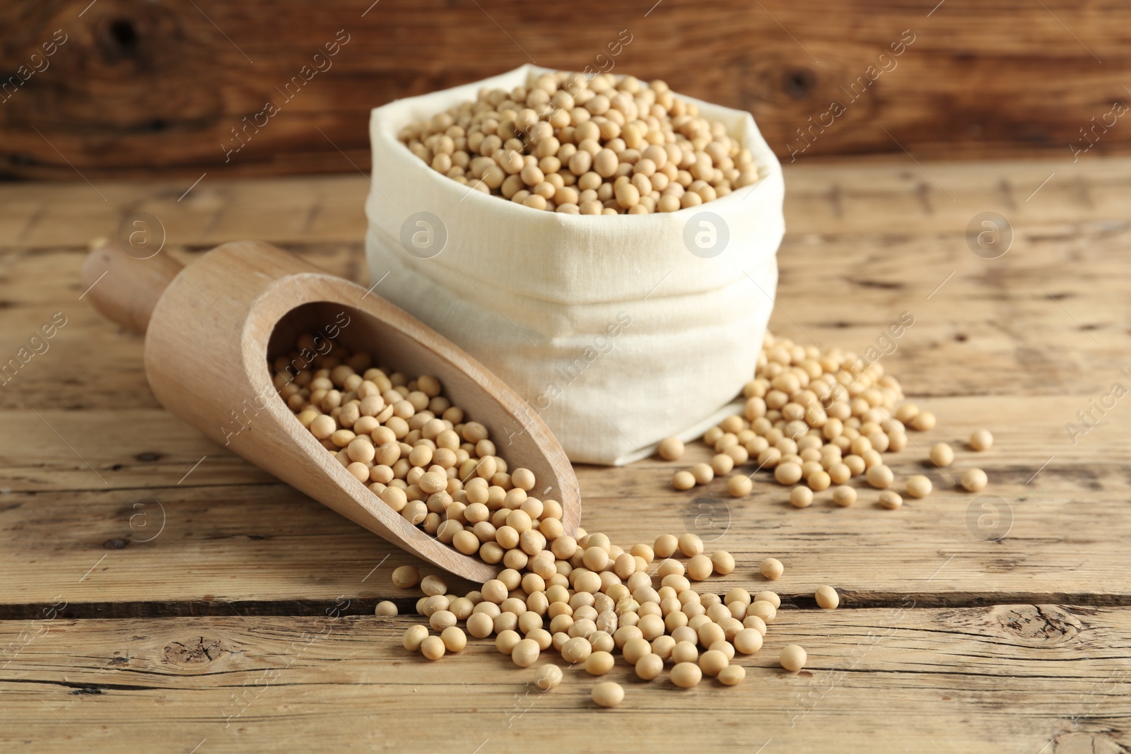 Photo of Scoop and sack with soy on wooden table