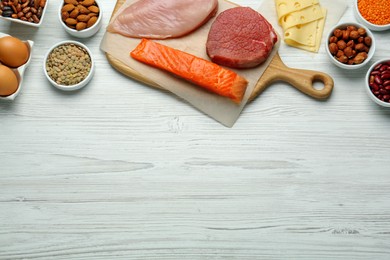 Photo of Different fresh products on white wooden table, flat lay and space for text. Sources of essential amino acids