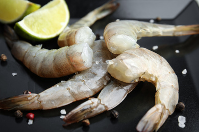 Photo of Fresh raw shrimps with lime on plate, closeup