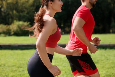 Healthy lifestyle. Couple running in park on sunny day, closeup