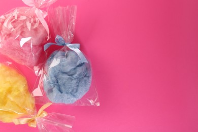 Photo of Packaged sweet cotton candies on pink background, flat lay. Space for text