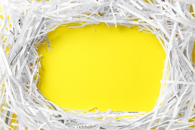 Photo of Frame of shredded paper strips on yellow background, flat lay. Space for text