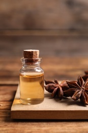 Bottle of essential oil and anise on wooden table