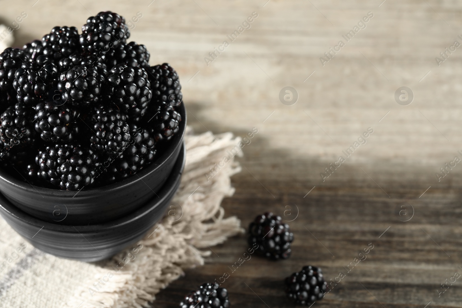 Photo of Fresh ripe blackberries on rustic wooden table, closeup. Space for text