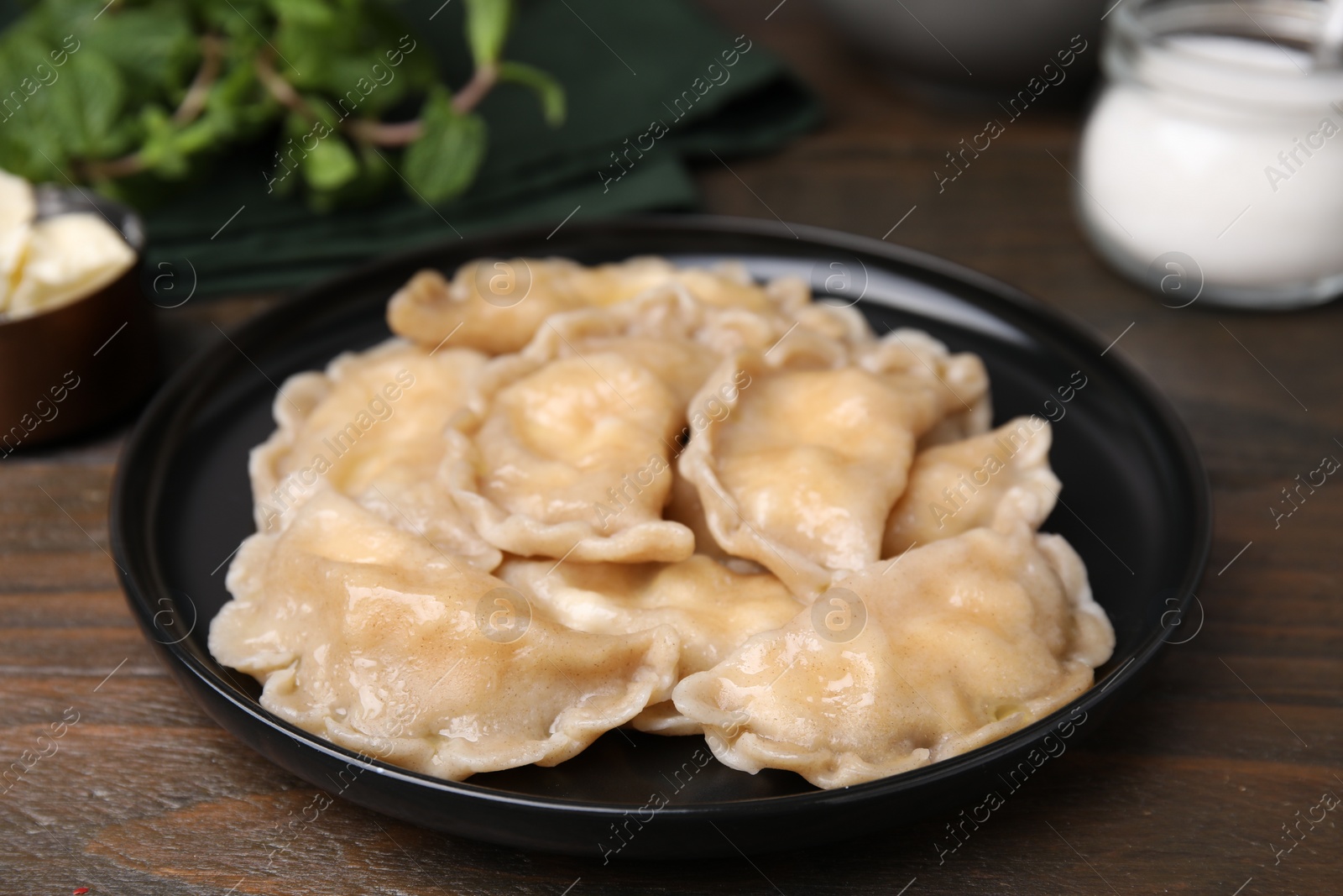 Photo of Plate of delicious dumplings (varenyky) with cottage cheese on wooden table, closeup
