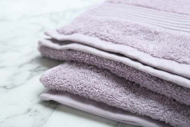 Violet terry towels on white marble table, closeup. Space for text