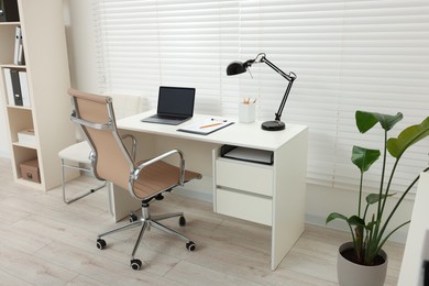 Photo of Doctor's workplace. Chair, laptop and clipboard on white table in clinic