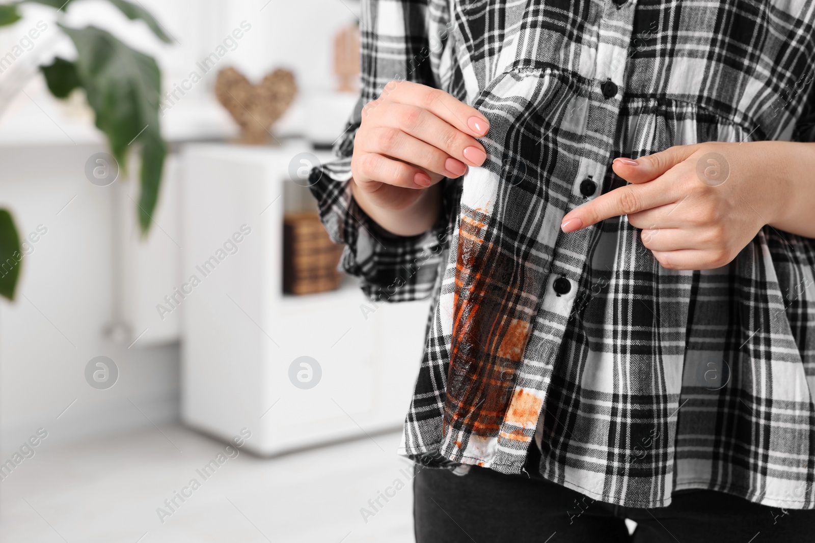 Photo of Woman showing stain from sauce on her shirt against blurred background, closeup. Space for text