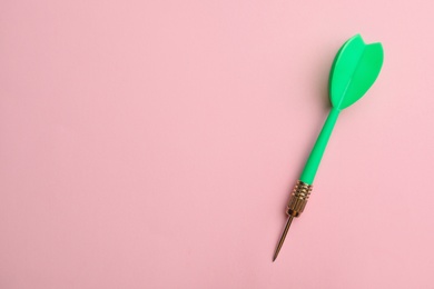 Photo of Green dart arrow on pink background, top view with space for text