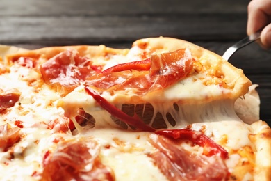 Woman holding shovel with slice of delicious hot pizza over table, closeup