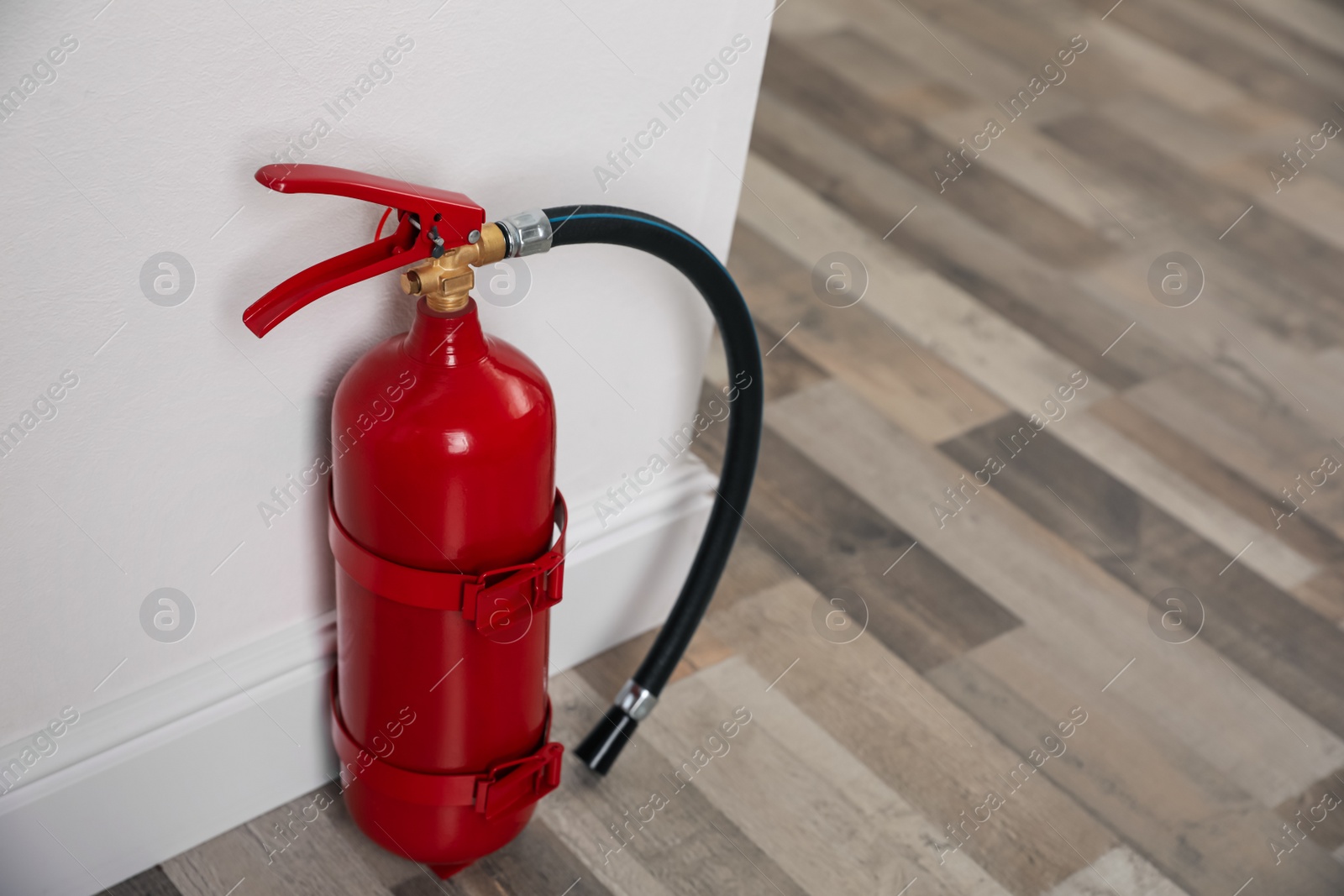 Photo of Fire extinguisher near white wall indoors. Space for text