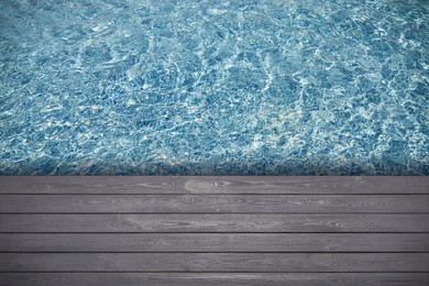 Image of Empty grey wooden surface near swimming pool with clear water. Space for design